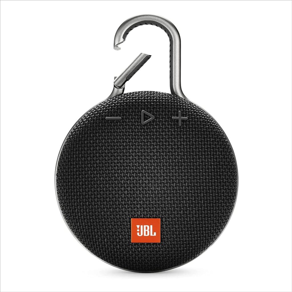 A bluetooth speaker by JBL. The speaker has a round body with buttons at the top of the sphere. Above the buttons is a carabeaner hook that allows you to hang the speaker.