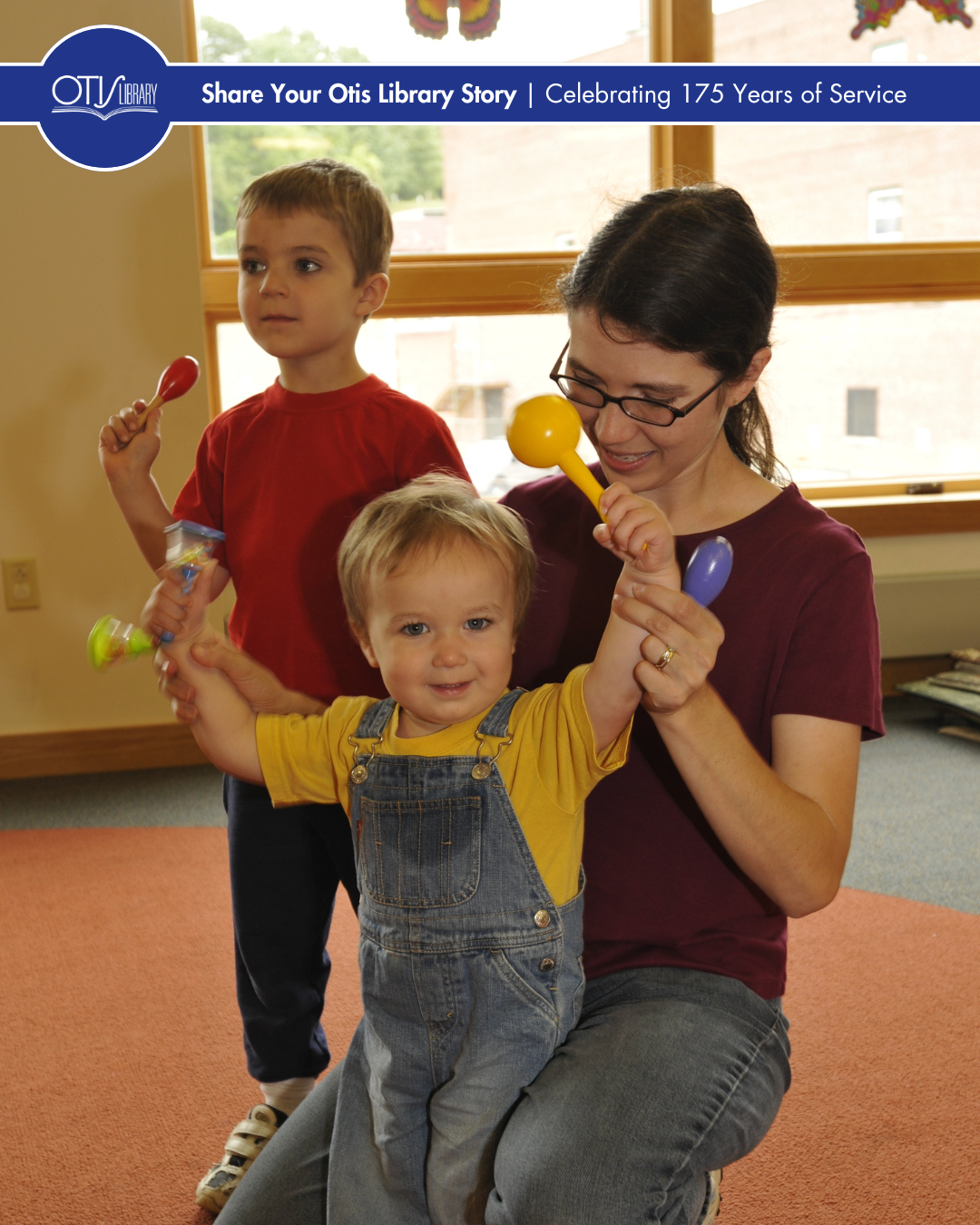 A young mom helps her toddler play with maracas during storytime.